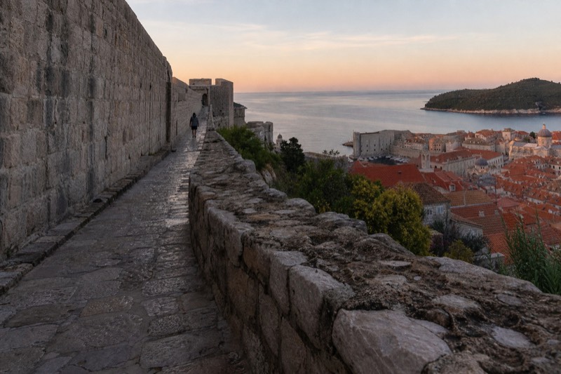 The great limestone wall circuit of Dubrovnik, Croatia, photographed low along worn stone paving at dawn, dew on the battlements