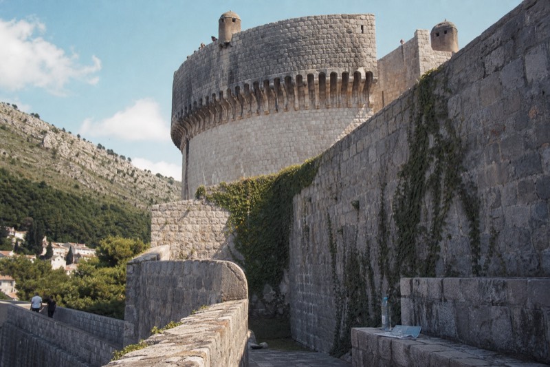 Late spring sun warms the curved round bastion of Minčeta fortress where it rises over Dubrovnik's walls, viewed from the ramparts below