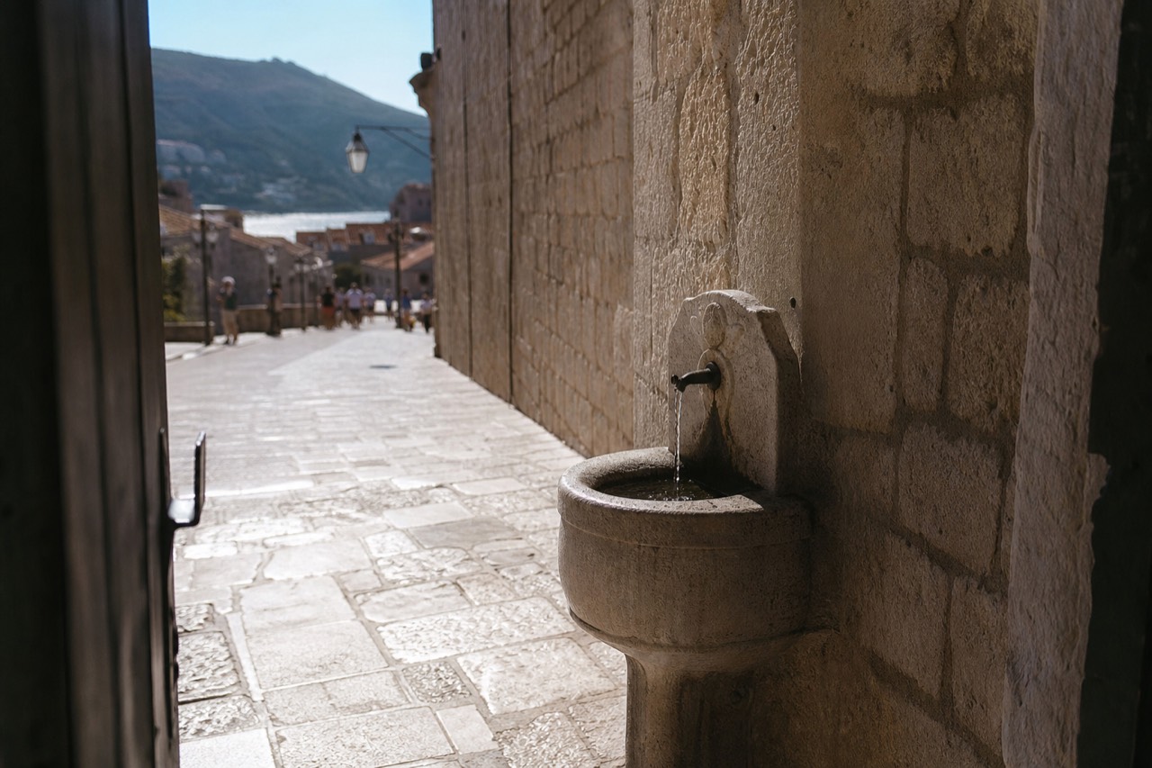 A stone drinking fountain beside a limestone street in Dubrovnik Old Town