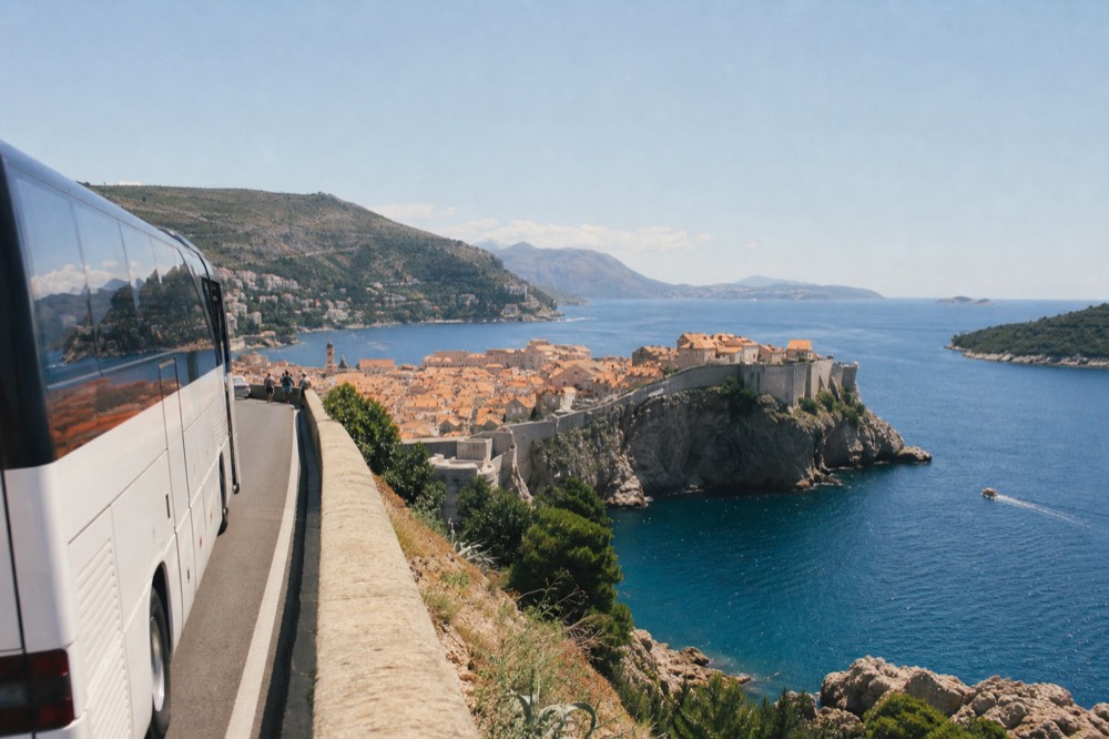 A tour bus parked on a coastal road above a walled Adriatic town