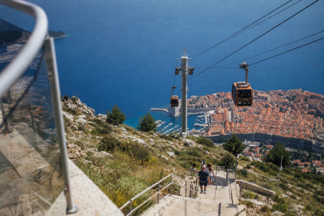 The Dubrovnik cable car cabins travelling up the hillside above the red roofs of the Old Town and the Adriatic sea
