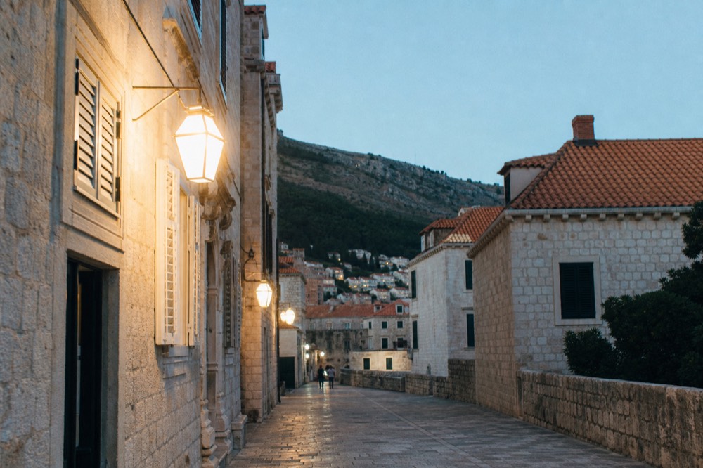 A limestone street inside Dubrovnik Old Town with shuttered stone buildings in morning light