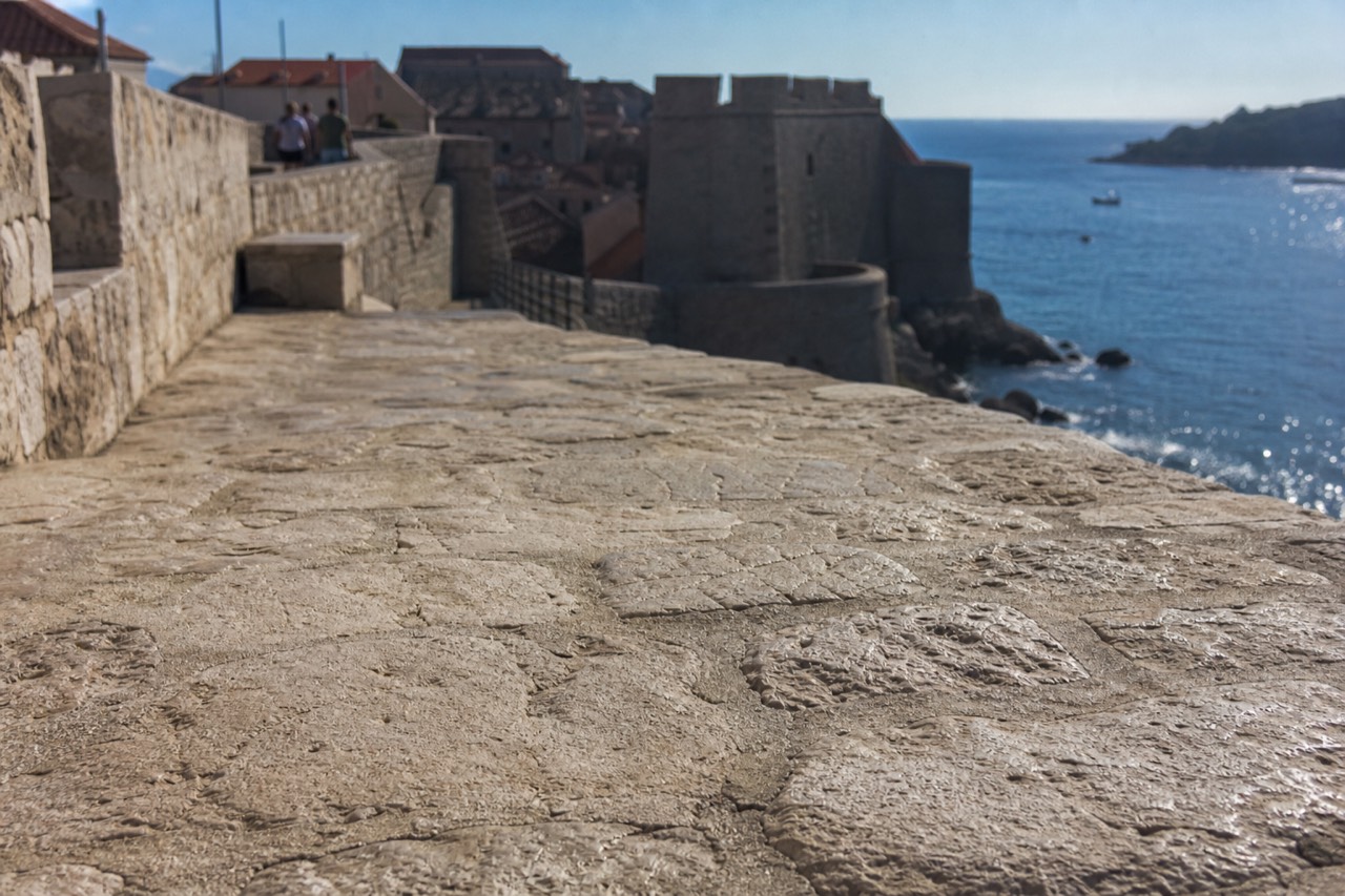Stone fortification walls rising above red rooftops and the Adriatic sea