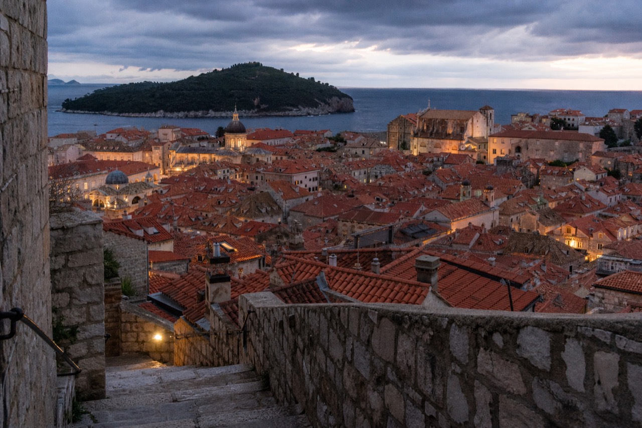 Dubrovnik Old Town rooftops under a dark evening sky with warm street lighting