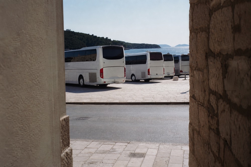 Long-distance coaches lined up at a coastal bus terminal with the sea behind