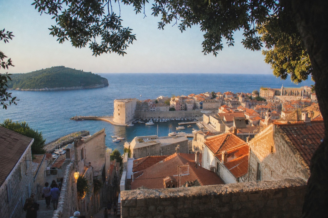 Warm evening light on the stone facades and lamp-lit lane of Dubrovnik Old Town