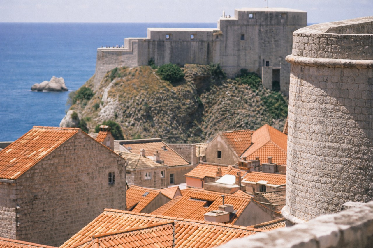 Stone city walls rising above red rooftops and the Adriatic sea
