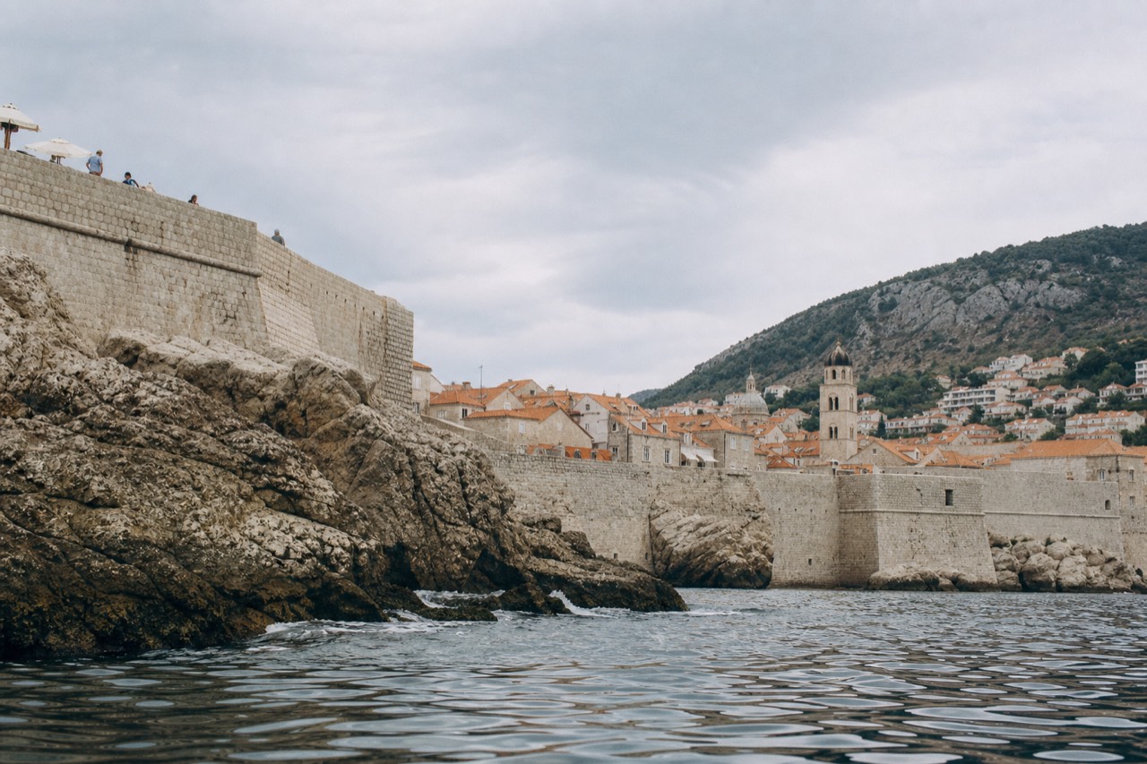 The stone rooftops and bell tower of Dubrovnik Old Town seen from the city walls above the sea