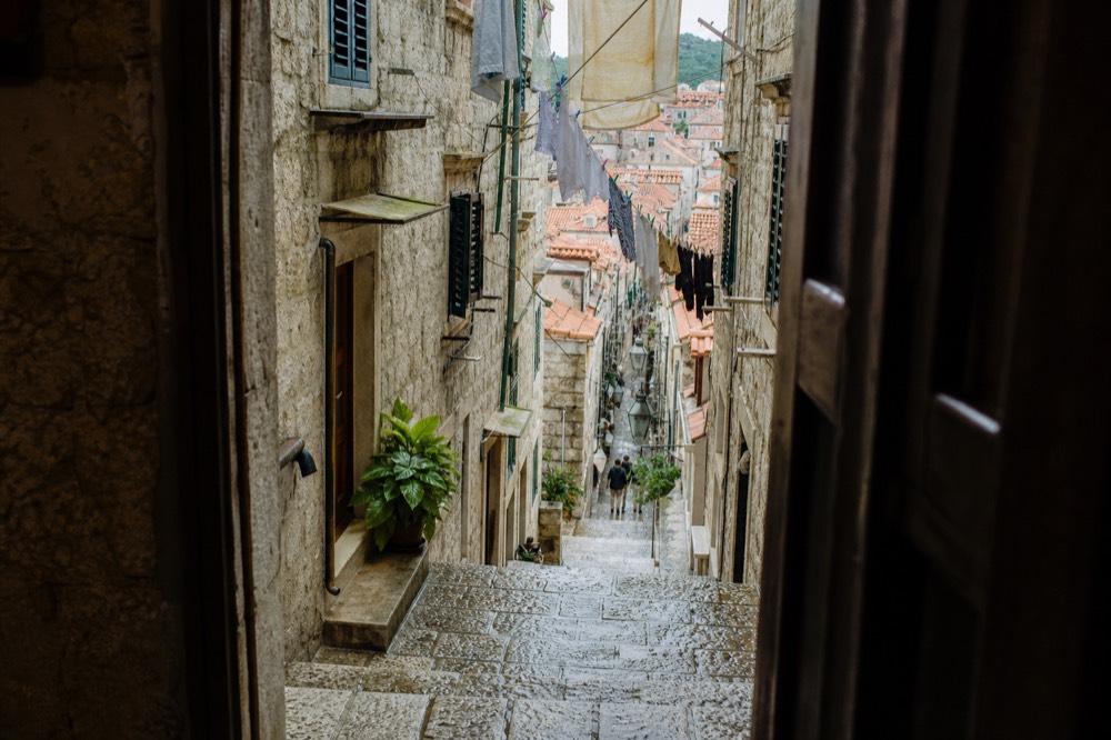 Stone stairway lane inside Dubrovnik Old Town with laundry lines and shuttered windows
