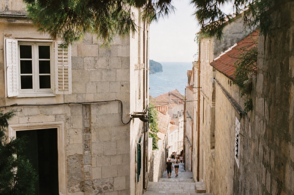 Narrow stone lane in Dubrovnik Old Town with worn limestone steps and old shutters