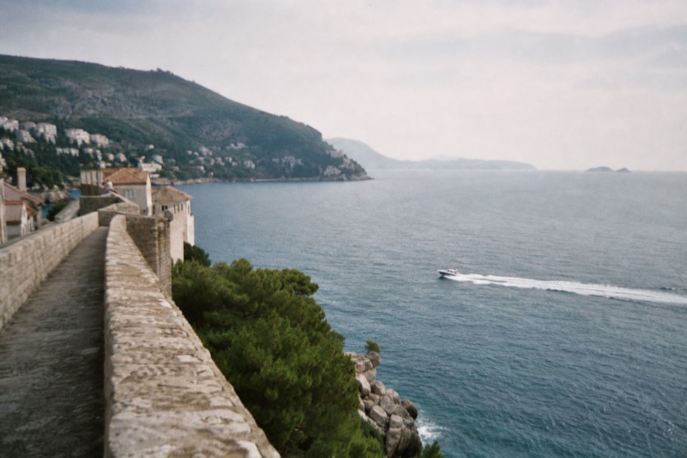 A speedboat cutting across open blue Adriatic water toward distant islands