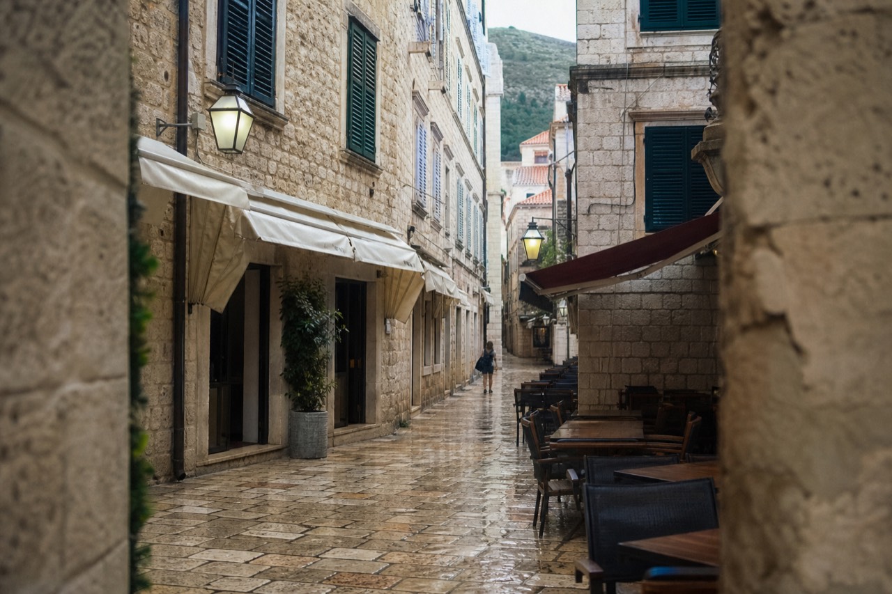 A stone street in Dubrovnik Old Town with café tables and shuttered shopfronts