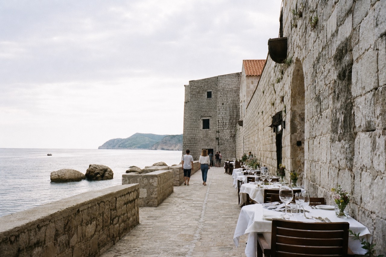 A stone alley in Dubrovnik Old Town with restaurant tables set beside a limestone wall