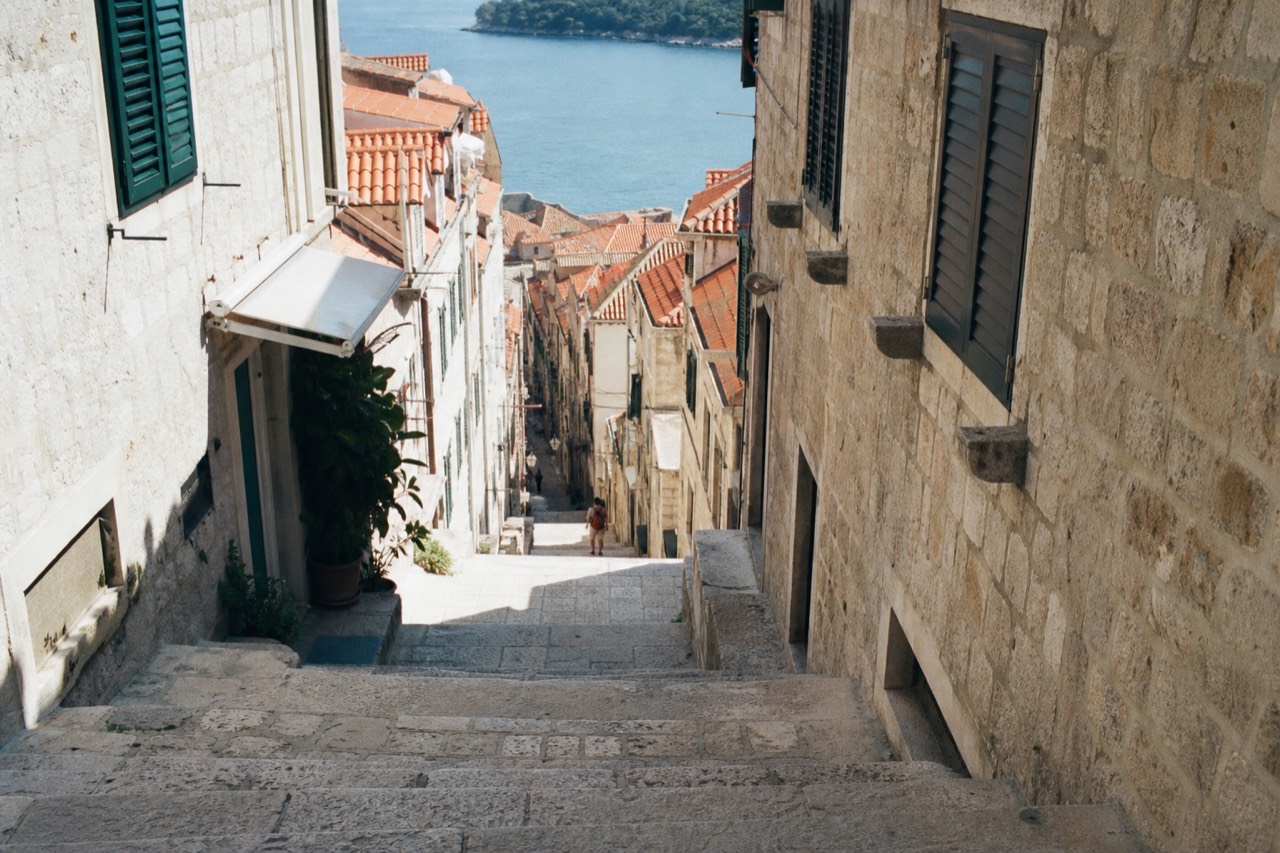 Sunlit limestone street in Dubrovnik Old Town with shuttered stone buildings