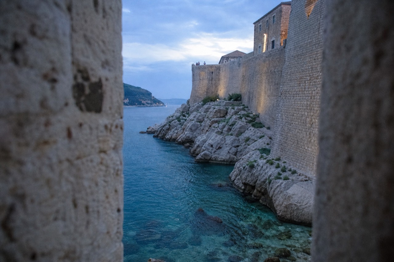 Clear turquoise water lapping against limestone rocks below Dubrovnik's city walls