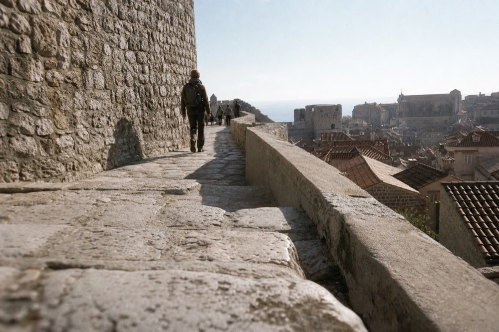Walkers on the stone wall path with the Old Town rooftops below