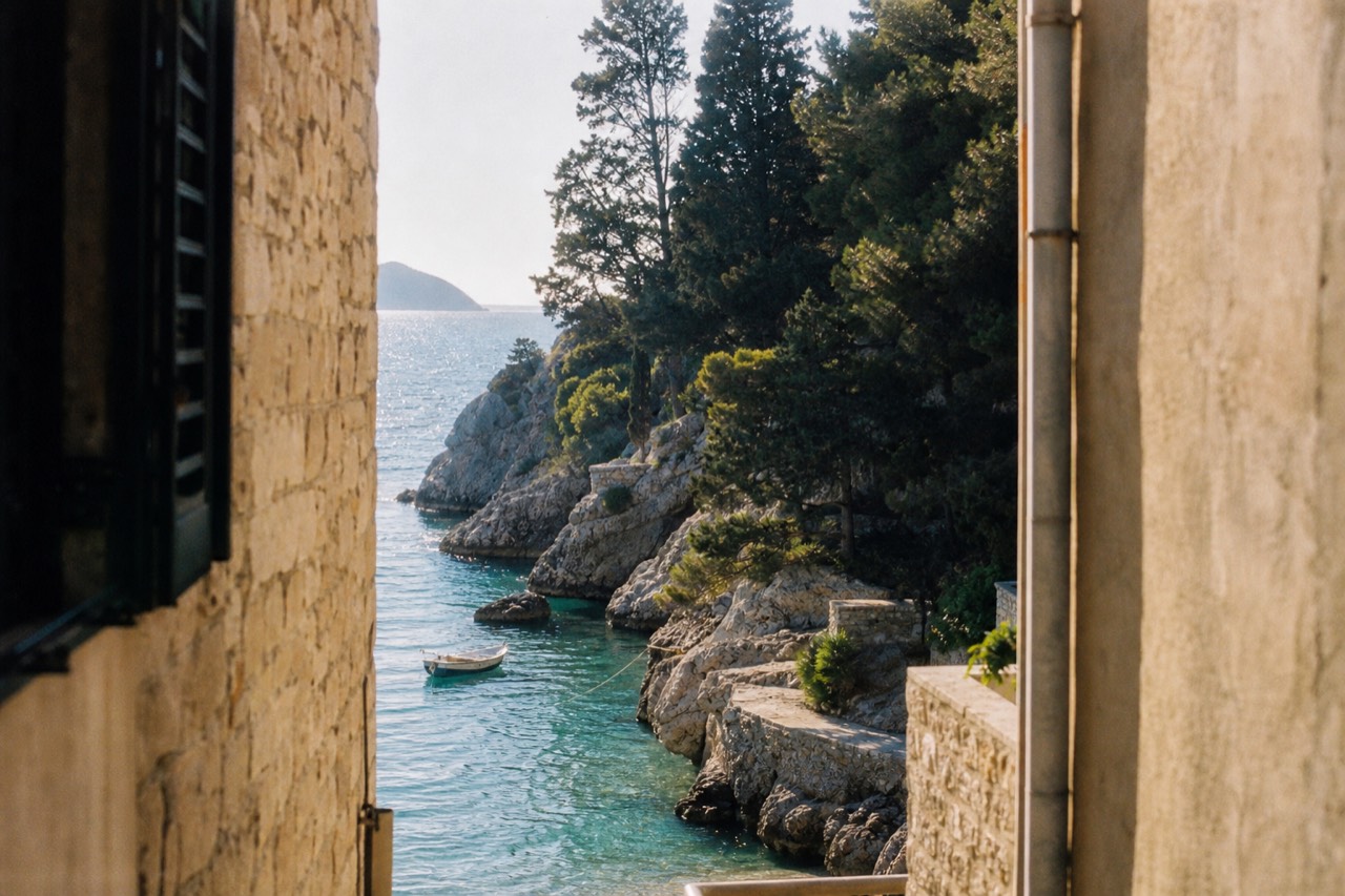 A small boat anchored in clear turquoise water beside a rocky Adriatic island shoreline