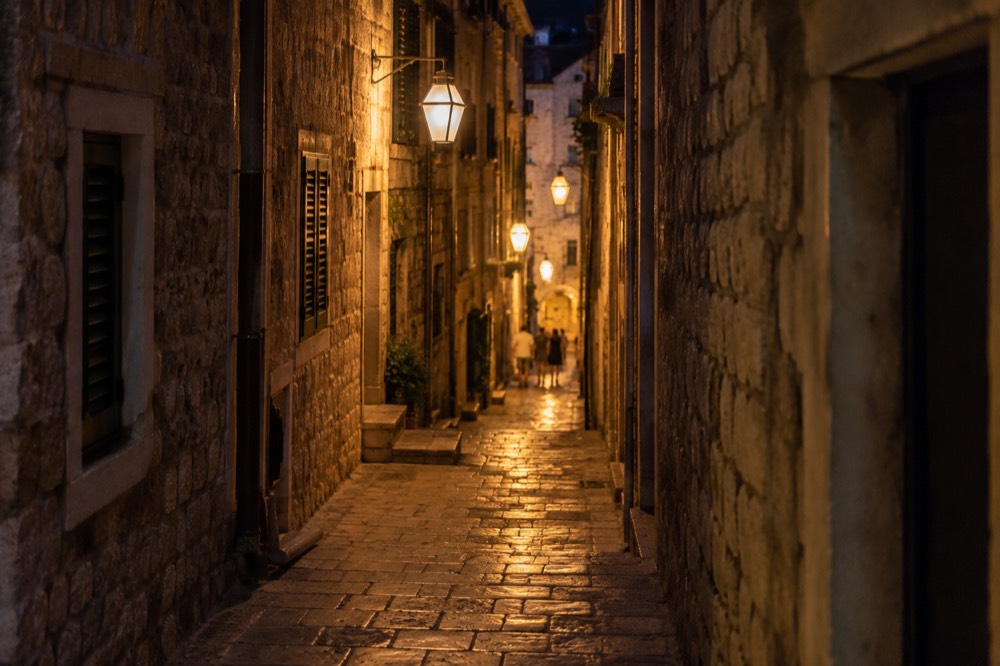 A narrow stone lane glowing under warm lamplight at night