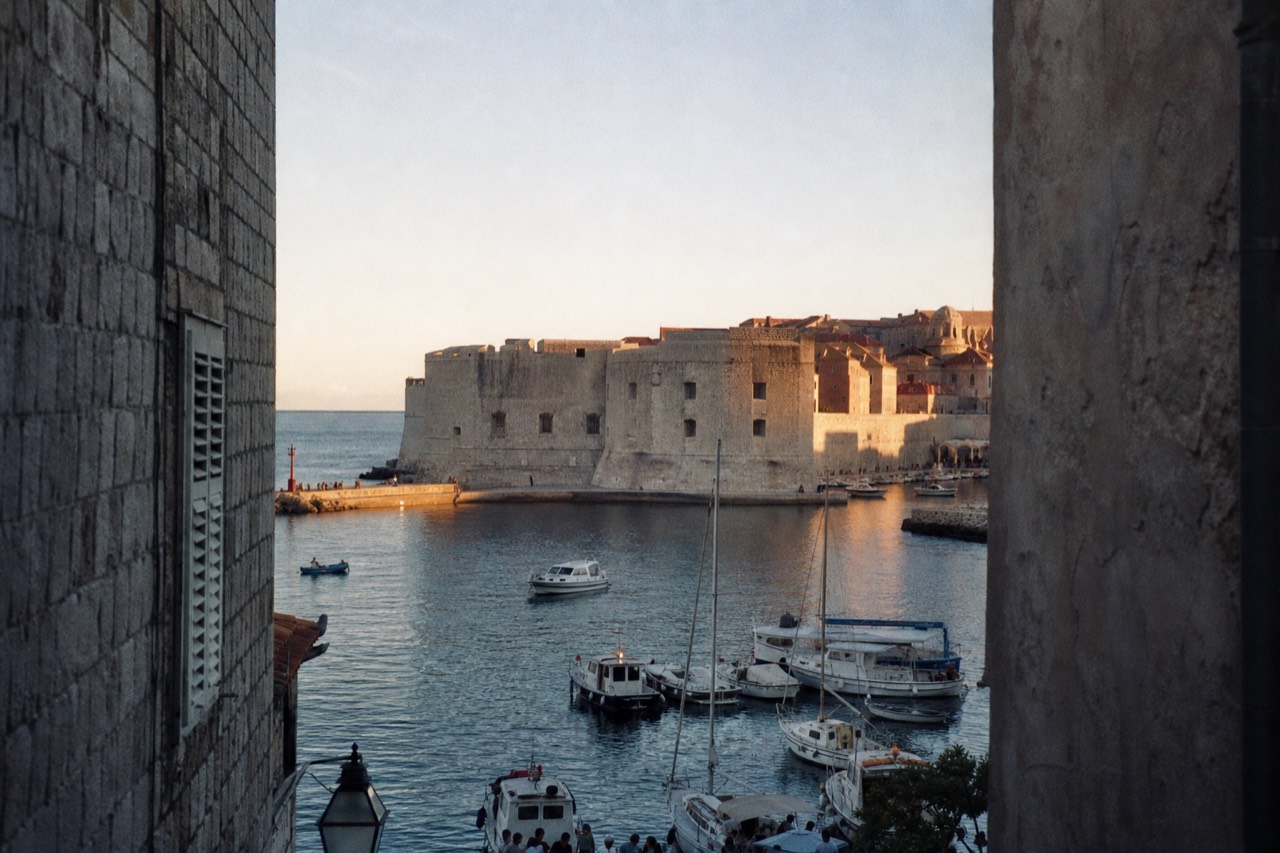 Lit stone buildings and a harbour front at dusk in a Croatian coastal town