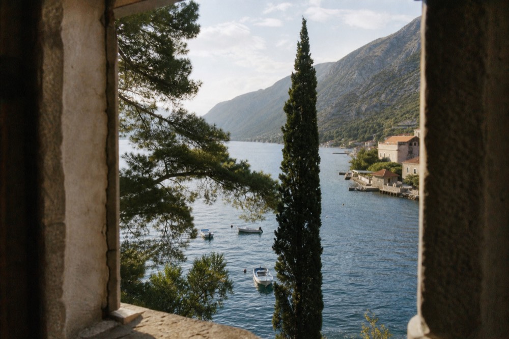 Small boats moored in the blue water of the Bay of Kotor beneath steep hillsides