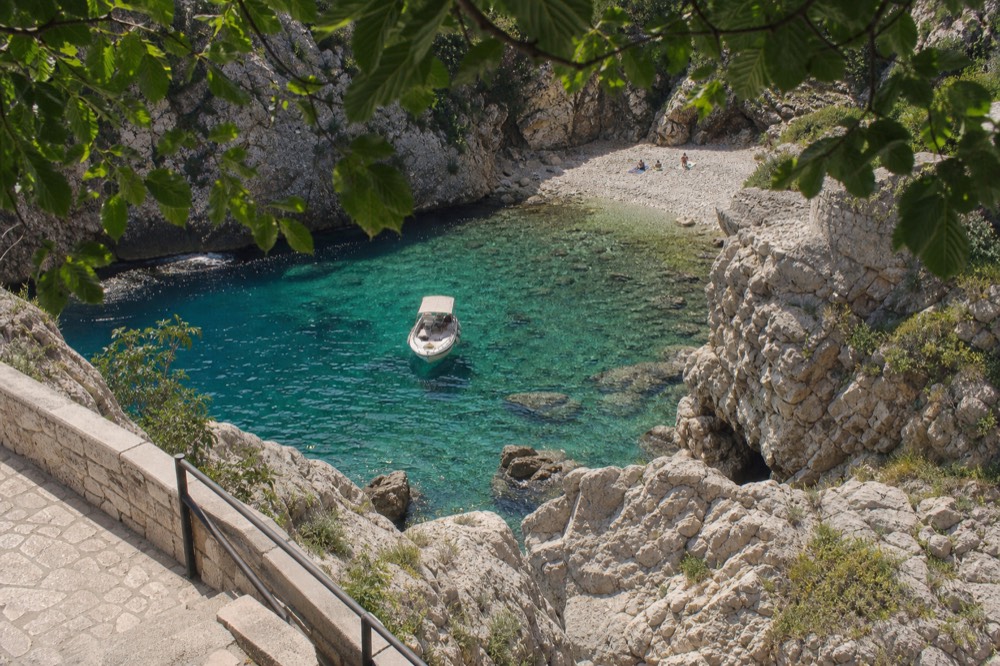 A small boat floating in a rocky cove with turquoise water near Dubrovnik
