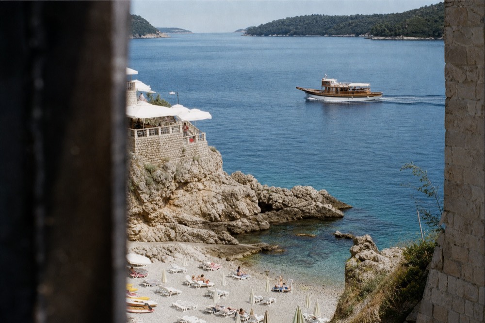 A traditional wooden boat cruising past green islands on calm blue Adriatic water