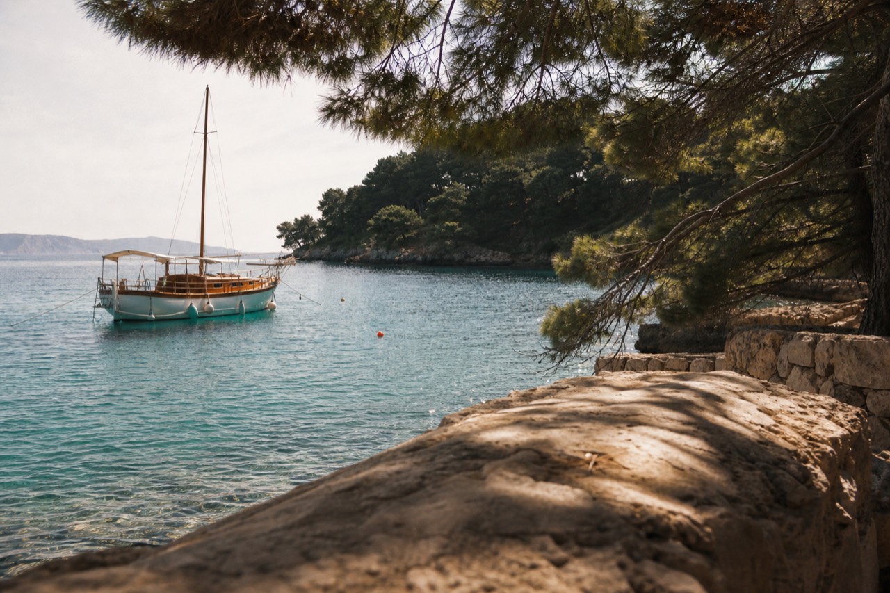 A wooden boat anchored in a calm turquoise bay beside a green island coastline