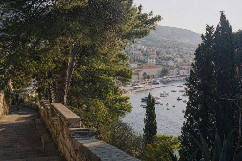 A small coastal town with a stone quay, moored boats and hills rising behind the rooftops