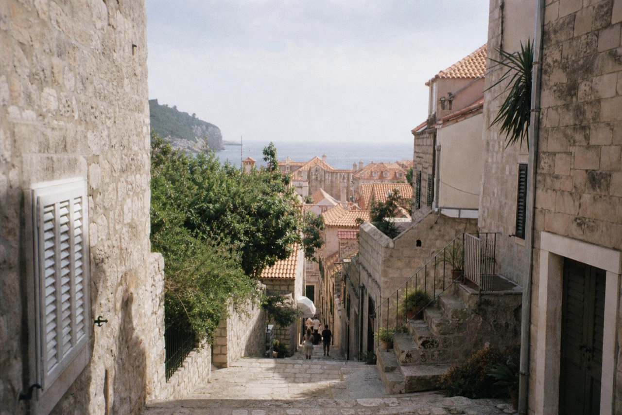 Sunlit limestone street in Dubrovnik Old Town with stone steps and shutters