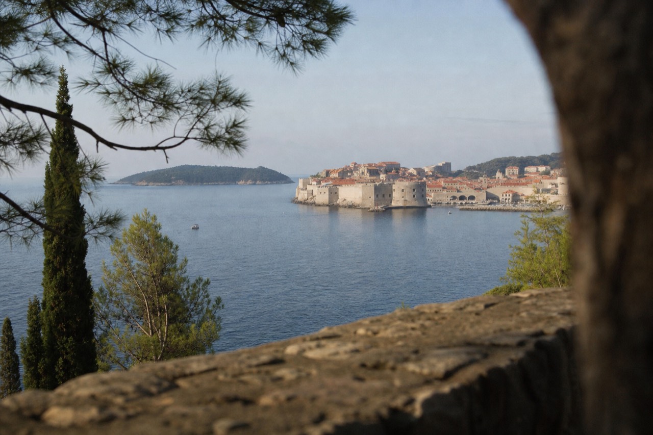 The walled Old Town of Dubrovnik seen from the sea on a calm morning with red rooftops and the island of Lokrum in the distance