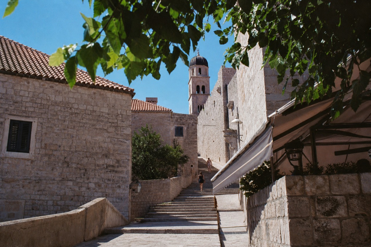 Stone street in Dubrovnik Old Town with limestone steps rising toward a church tower