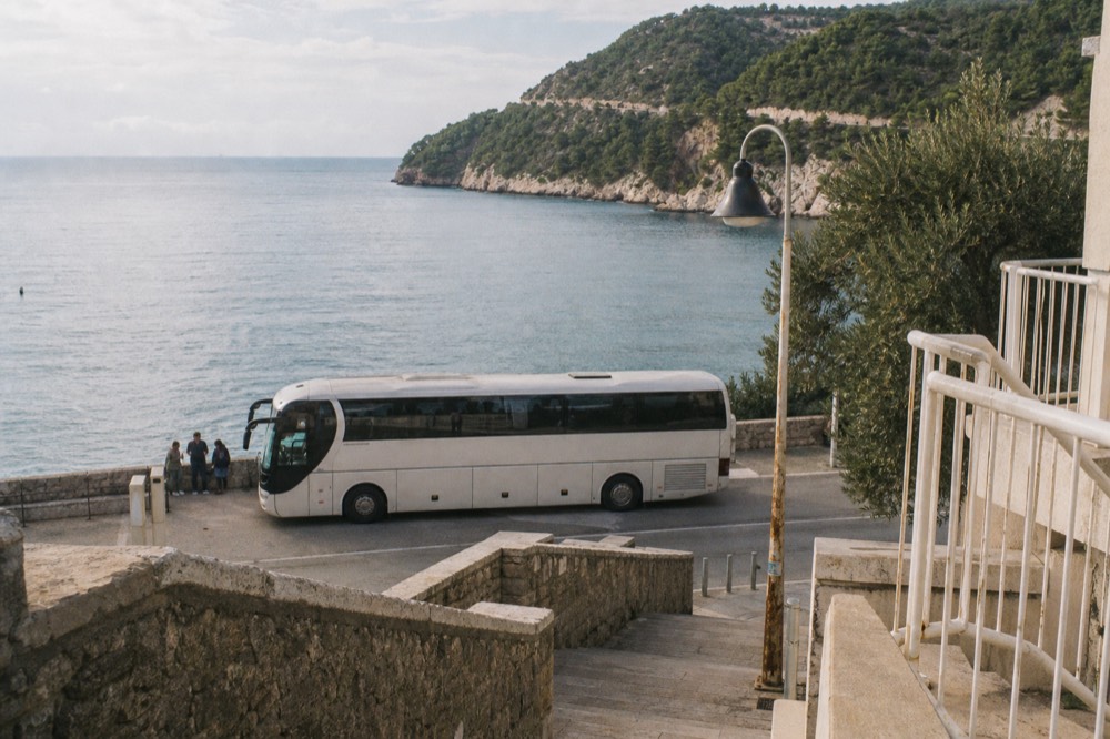 An intercity bus parked at a coastal station with the sea behind it