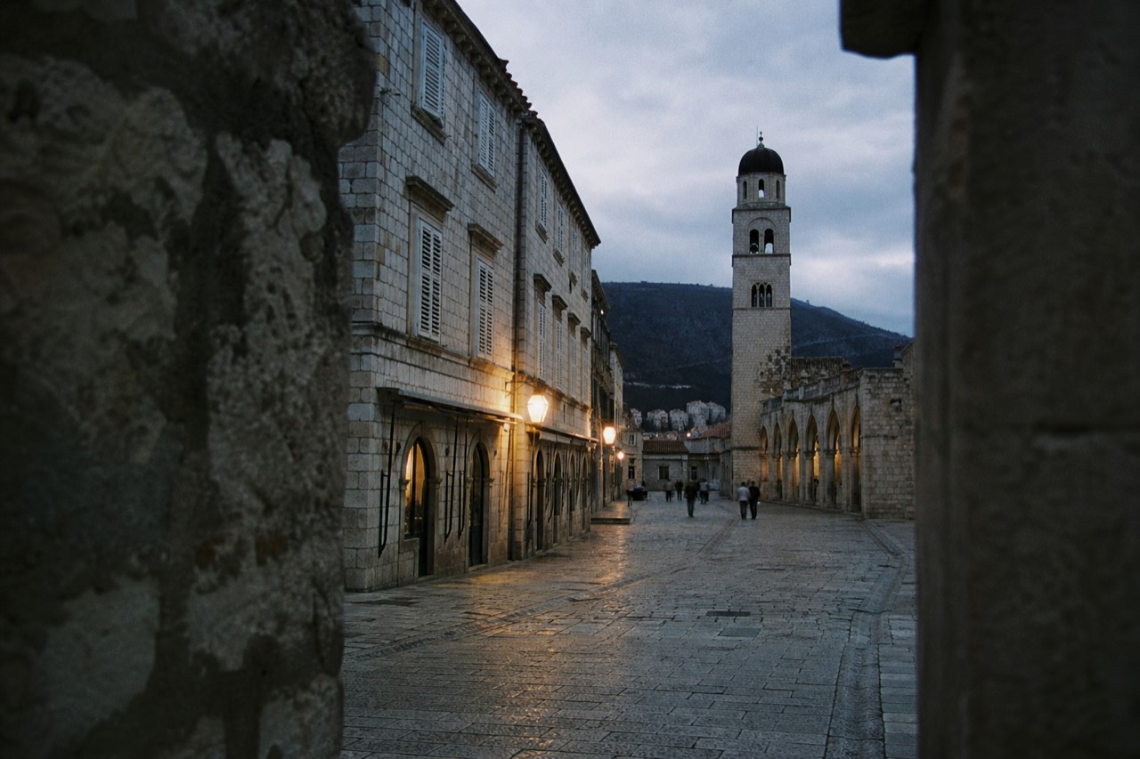 Empty stone streets of Dubrovnik Old Town under a grey winter sky with the bell tower in the background