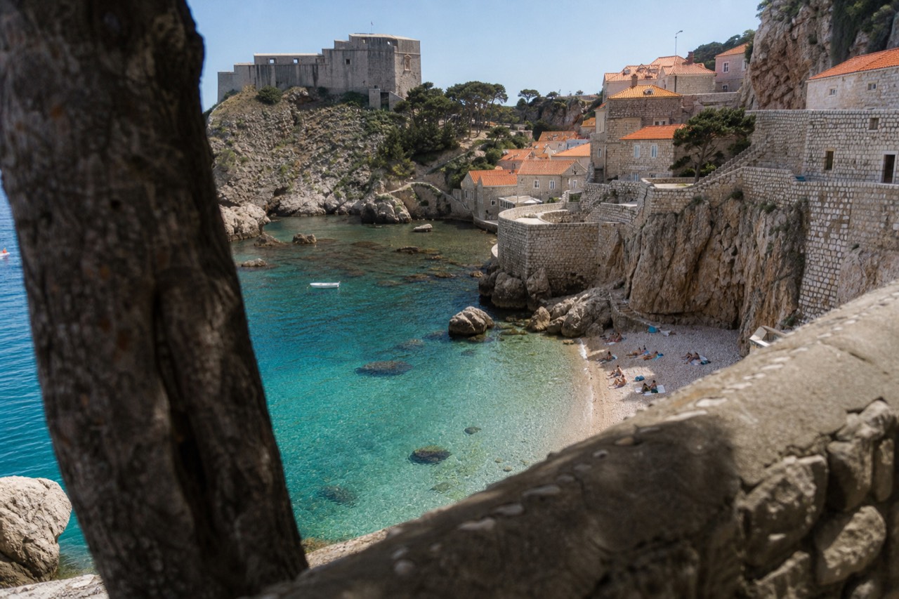 A quiet pebble beach with turquoise water and rocky cliffs in Dubrovnik