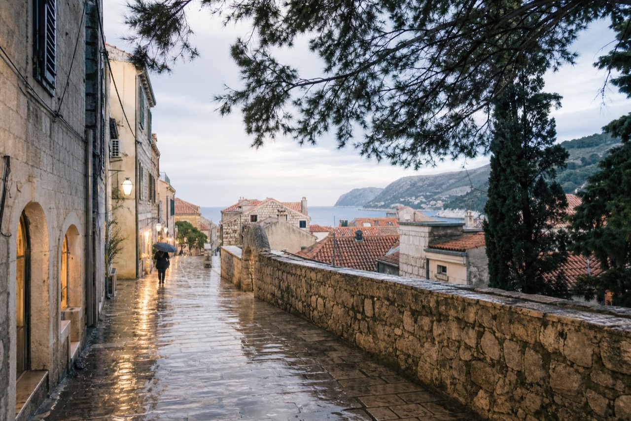Wet limestone street in Dubrovnik Old Town reflecting warm light from shop windows after rain