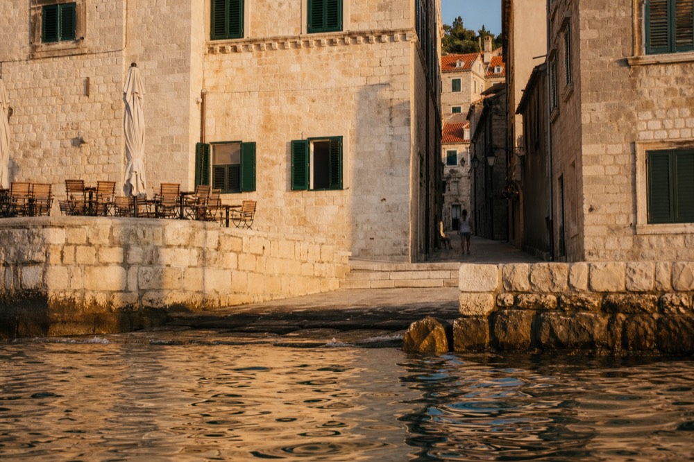 A stone lane in Dubrovnik Old Town with café tables and closed green shutters