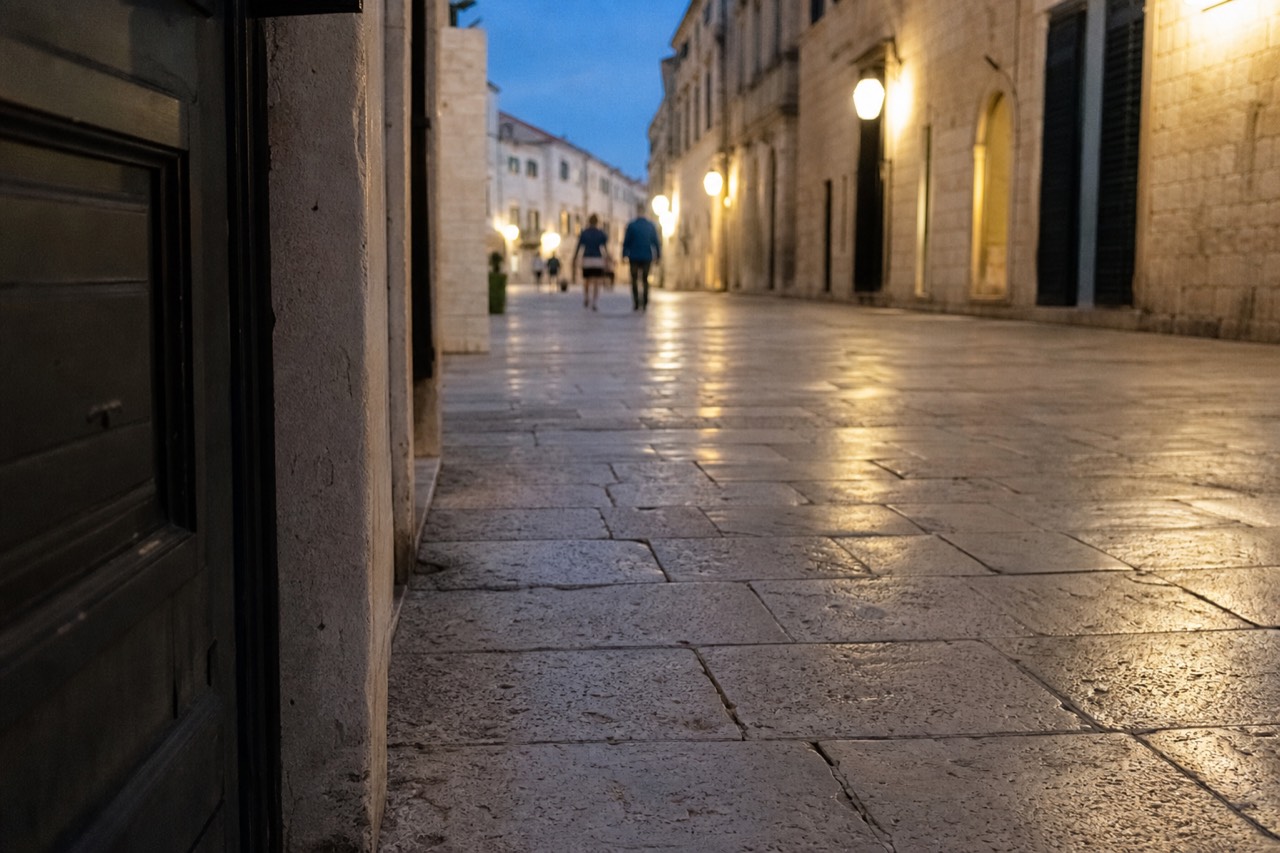 Close-up of the smooth limestone paving stones of Dubrovnik's Stradun, worn glossy by centuries of foot traffic