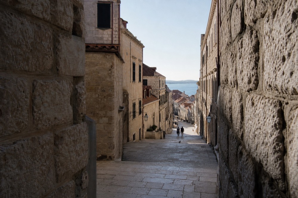 A wide limestone street in Dubrovnik Old Town lined with stone buildings under a clear sky