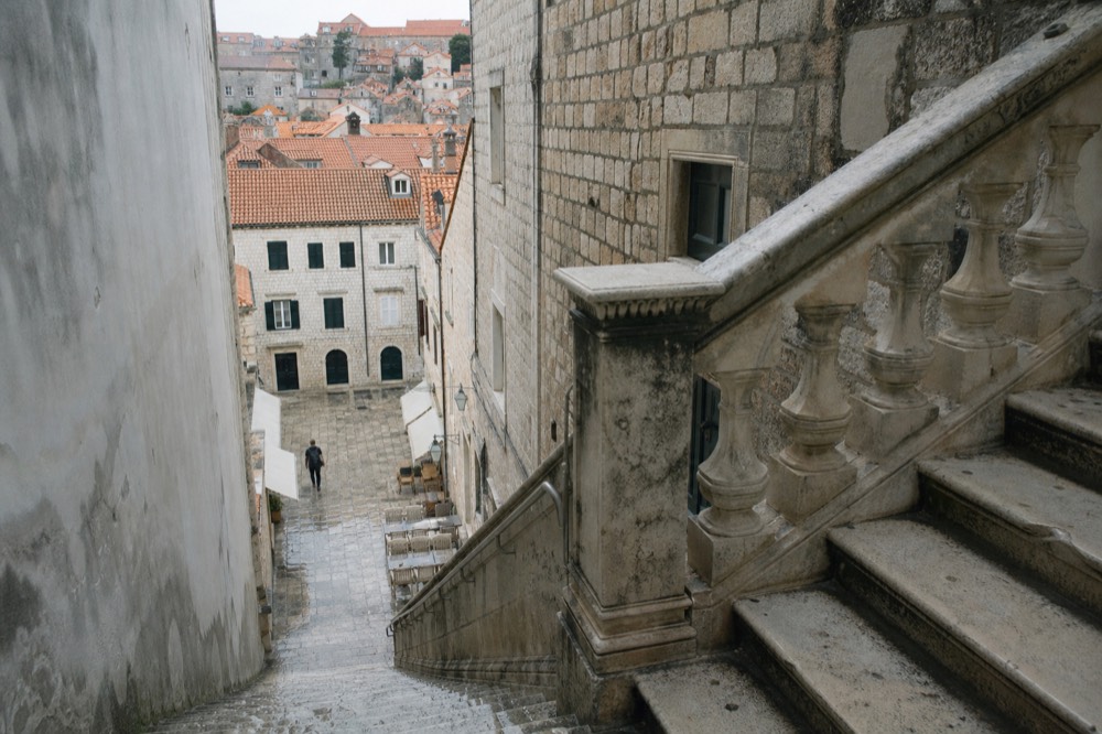 Wide baroque stone staircase descending toward a small square lined with buildings in Dubrovnik