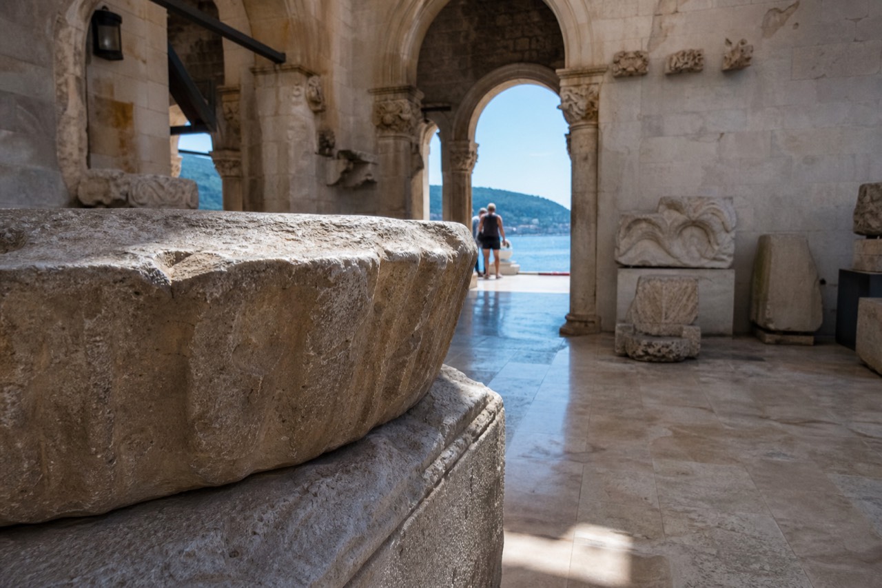 Stone museum interior in Dubrovnik with arched doorways and exhibits along the walls