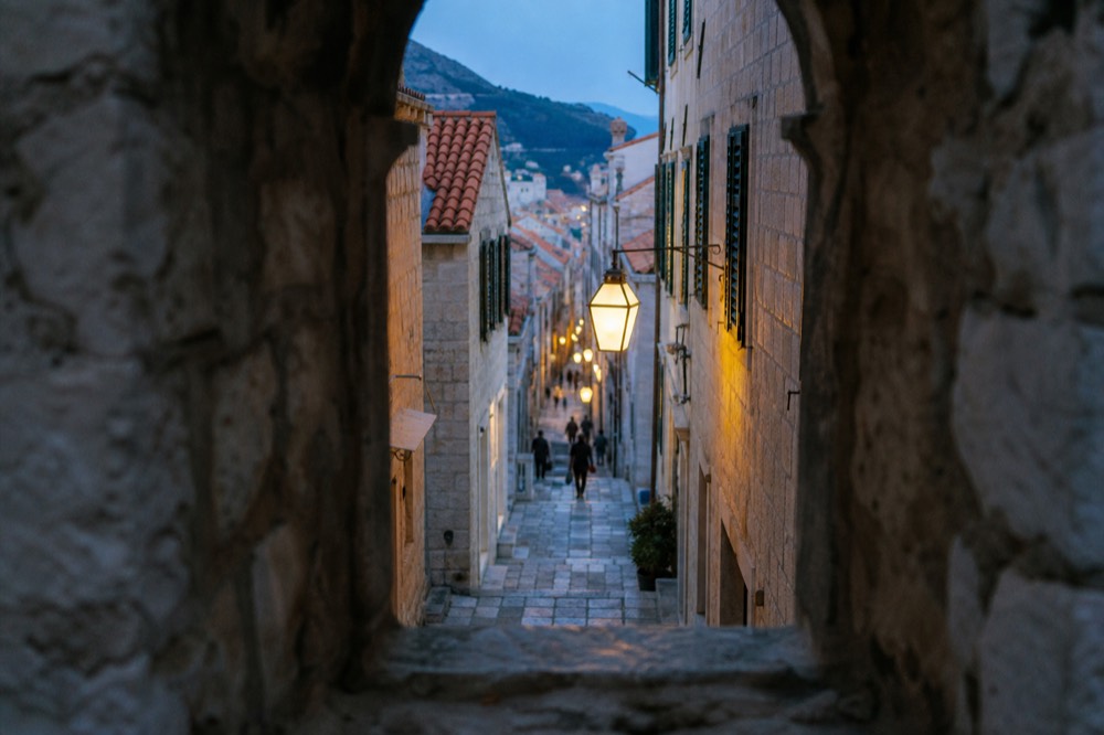 Narrow limestone street in Dubrovnik Old Town with stone steps and shuttered facades