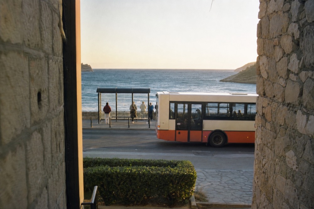 Local bus at a stop on a coastal road with the sea behind it