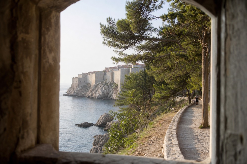 A coastal path with the stone city walls visible above the shoreline ahead