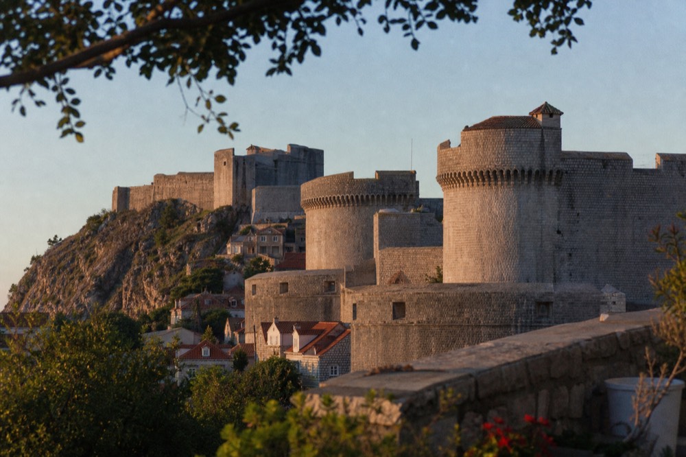 Stone fortification towers of the city walls rising above rooftops under a clear sky