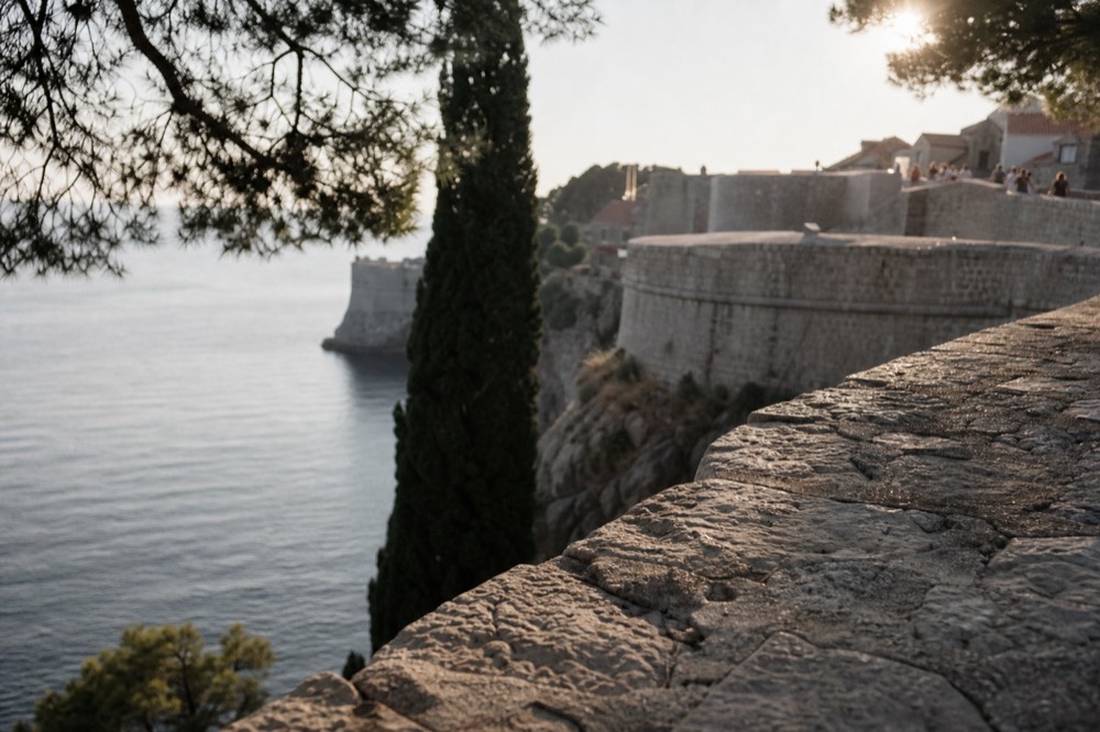 The city walls of Dubrovnik at sunset, with the stone fortifications and the Adriatic Sea