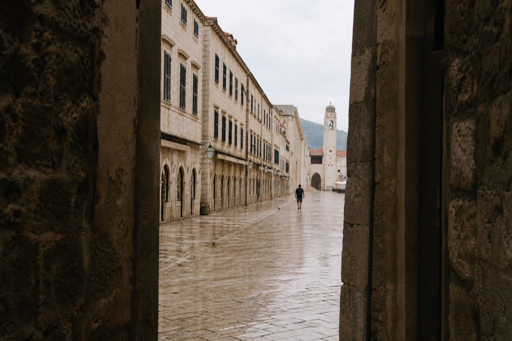 The Stradun in early morning light with limestone pavement and closed shutters, few people about