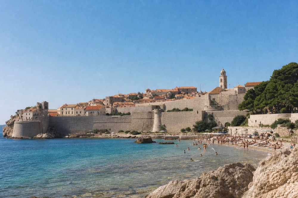 Banje Beach below Ploče with clear shallow water and the city walls behind