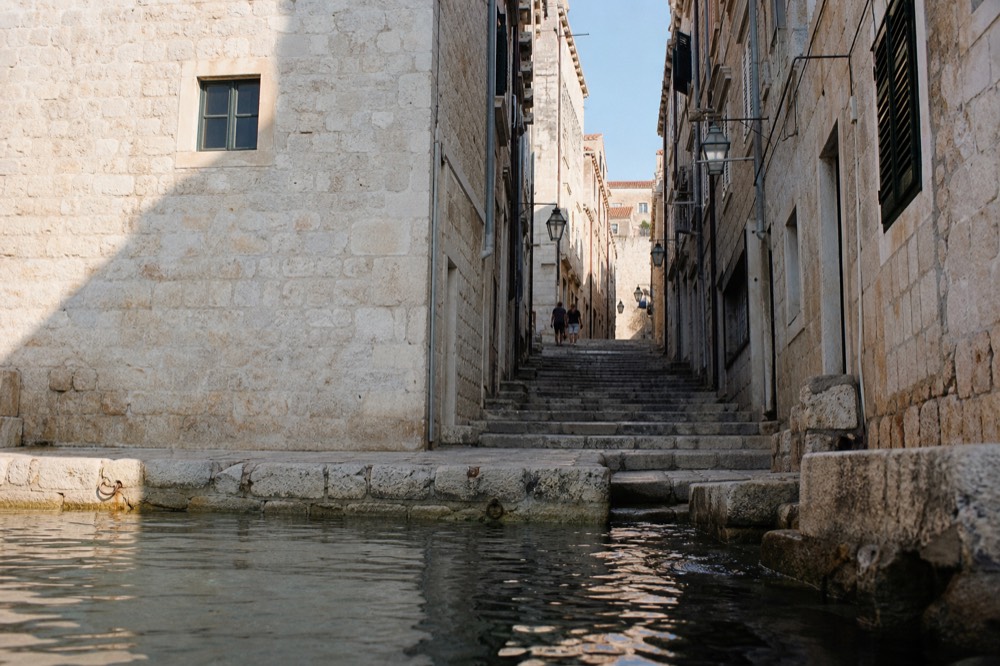 Narrow limestone street in Dubrovnik Old Town lined with stone buildings and shuttered windows