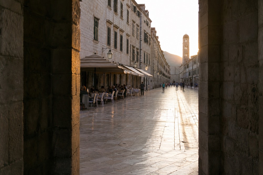 Evening light on the Stradun with cafe tables and stone facades in Dubrovnik Old Town