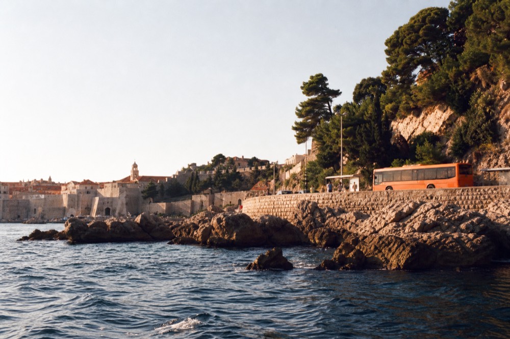 Orange city bus at a stop on a coastal road above Dubrovnik